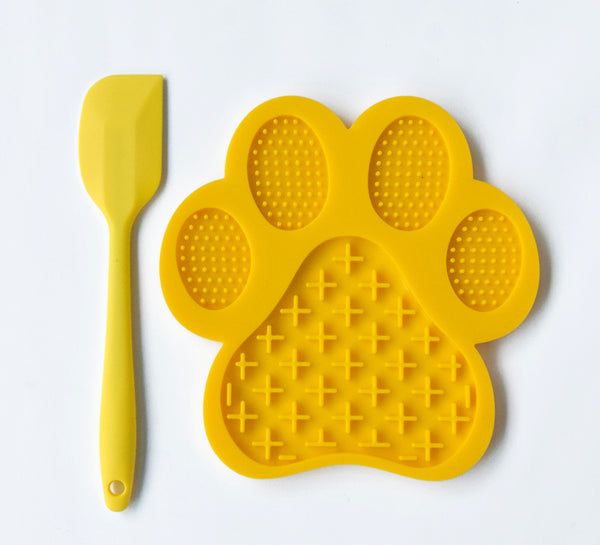 Non slip yellow lick mat and spatula white background